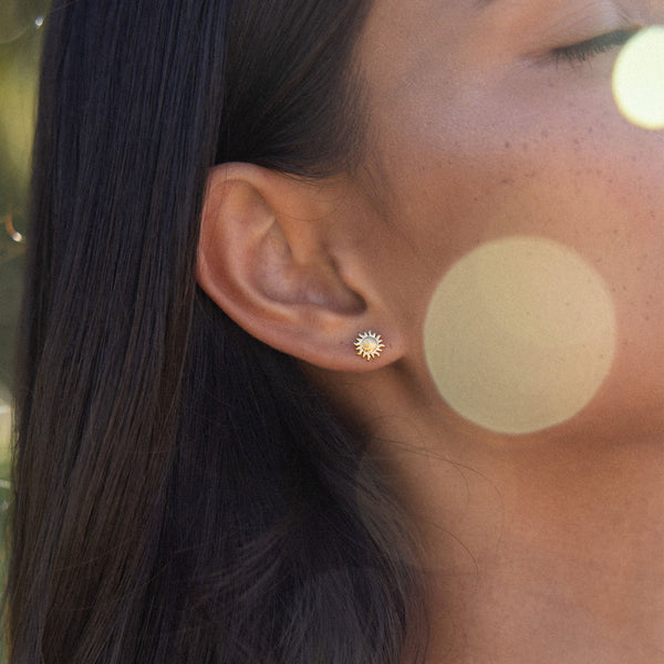 Goldene Ohrringe mit Sonnenmotiv, getragen von einer Frau, PURELEI inspiriert.