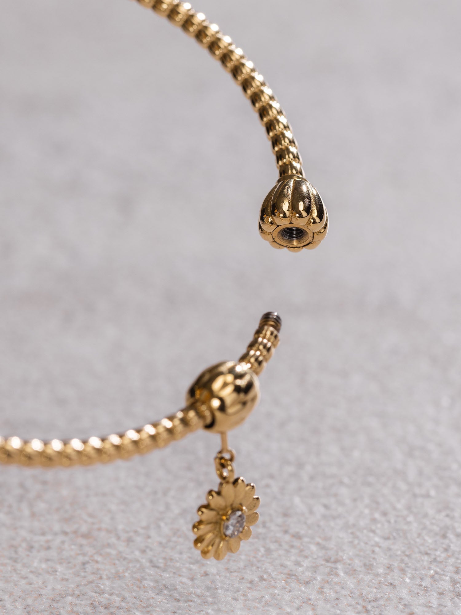 Lei Charm Armreif von PURELEI aus 14K vergoldetem Edelstahl mit Pikakeblüten-Design und zwei Stopper-Charms auf weißem Hintergrund