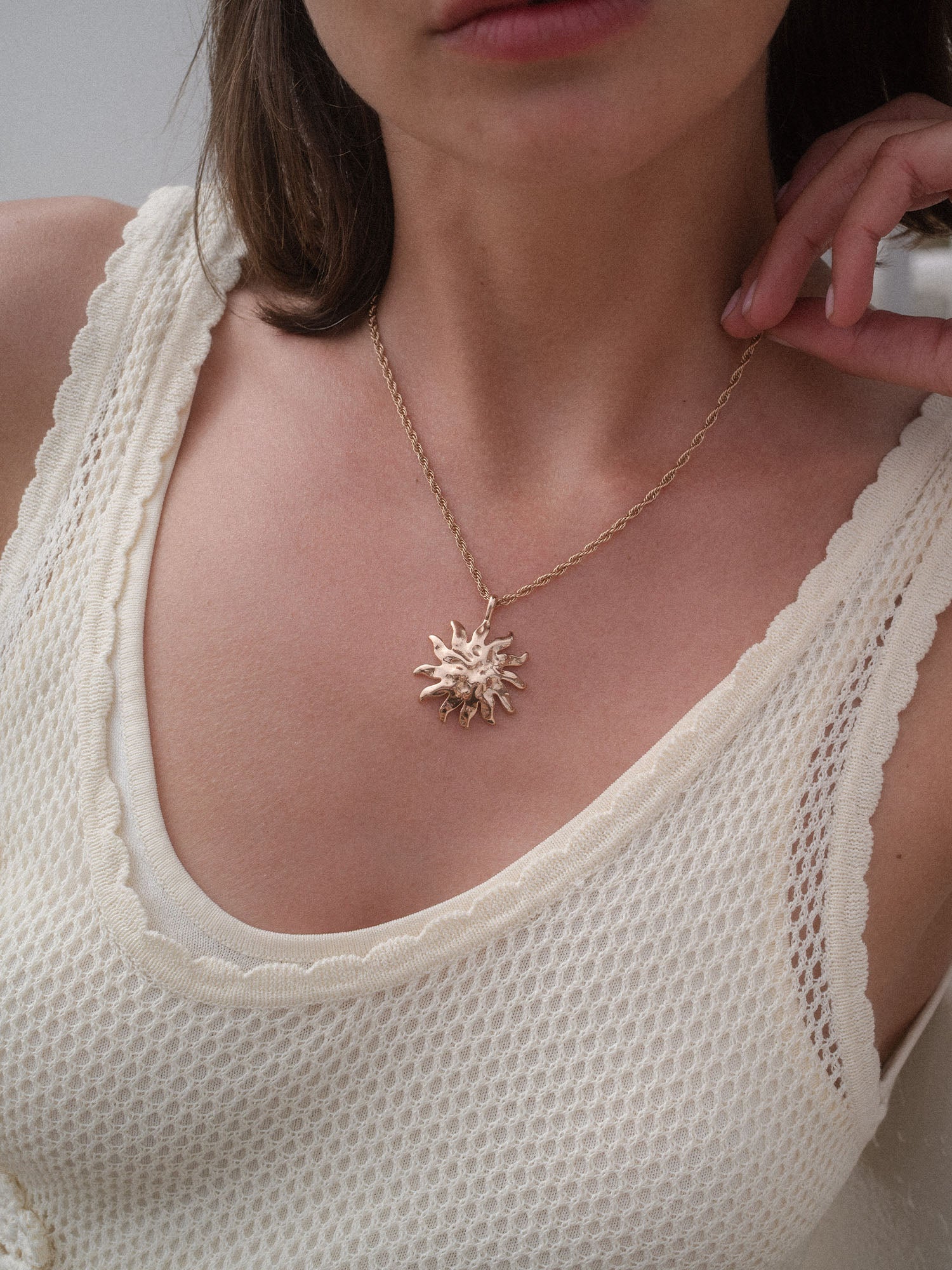 PURELEI Iconic Sun Charm aus goldfarbenem Edelstahl mit strukturiertem Sonnenanhänger, elegant und feminin getragen.